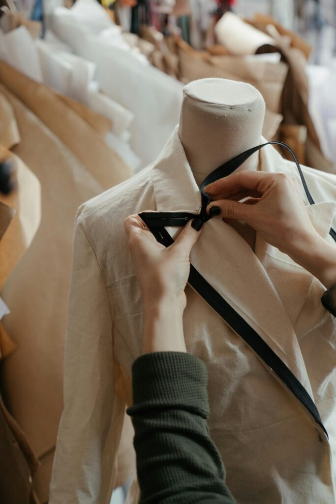 Close-up of tailor adjusting a garment on a mannequin, symbolizing fashion design in a creative studio.