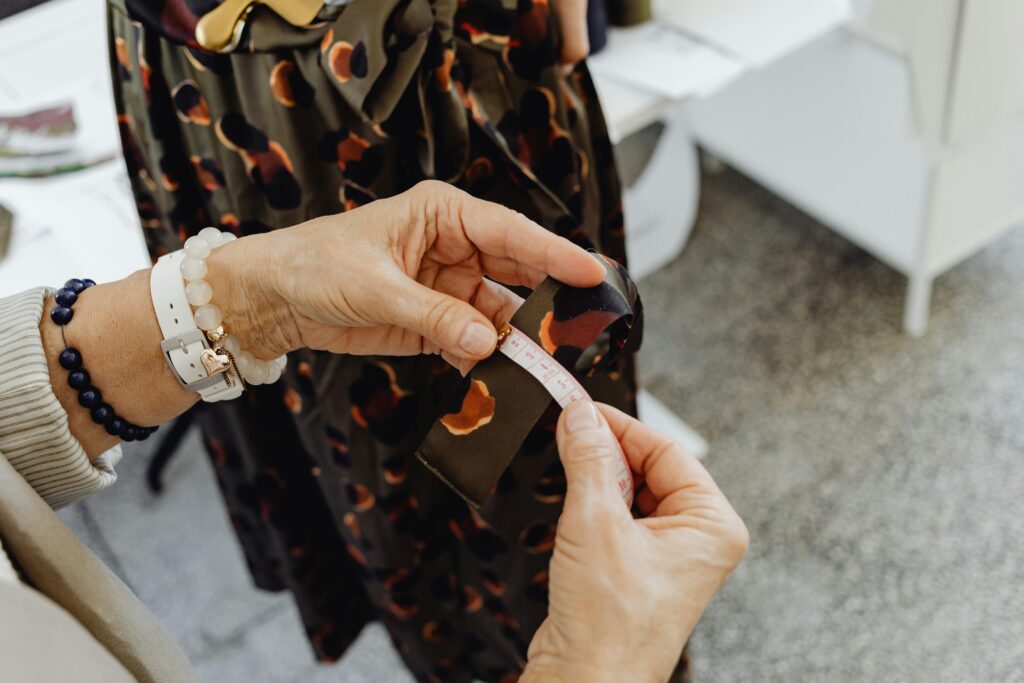 Detailed close-up of seamstress' hands measuring fabric with tape in a fashion studio setting.