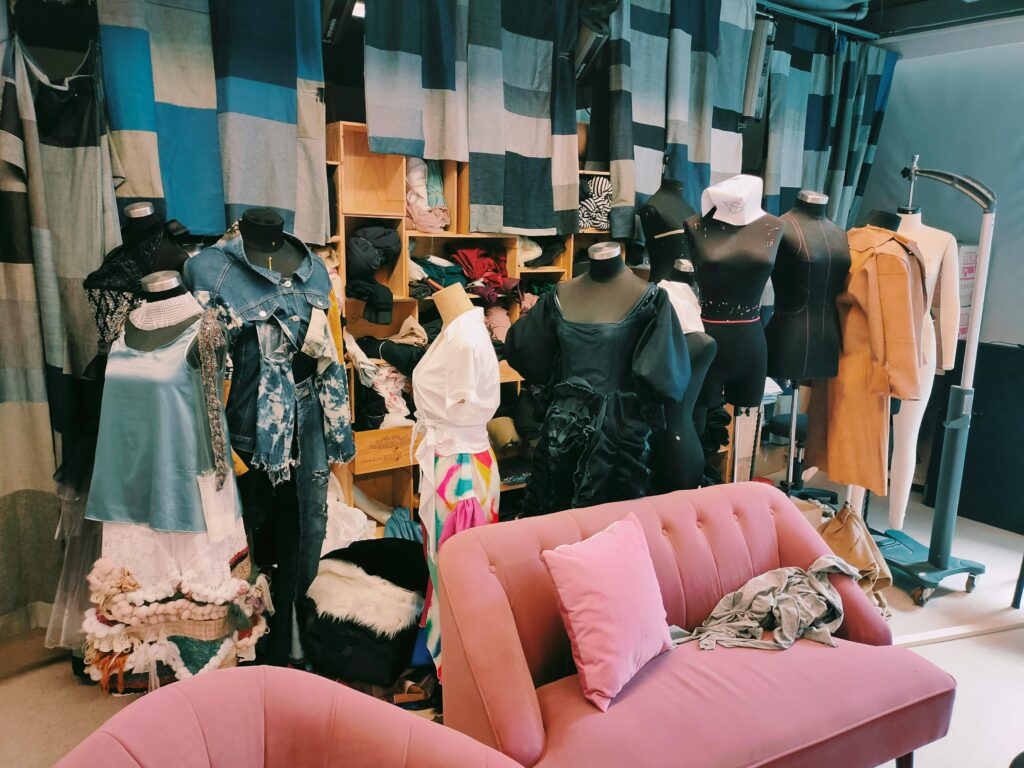 Explore a vibrant fashion studio showcasing mannequins dressed in diverse outfits and surrounded by various fabrics and textiles.